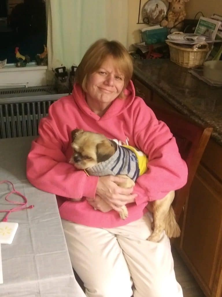 woman in pink sweatshirt holding a small dog