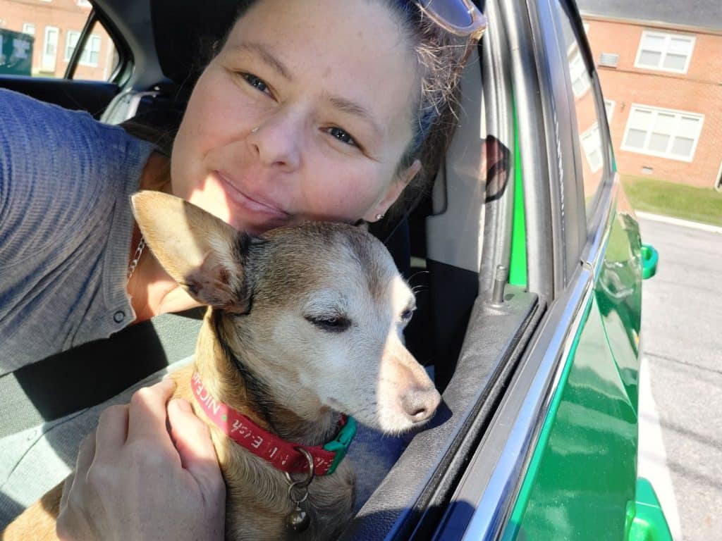 woman taking selfie in car while holding a small dog