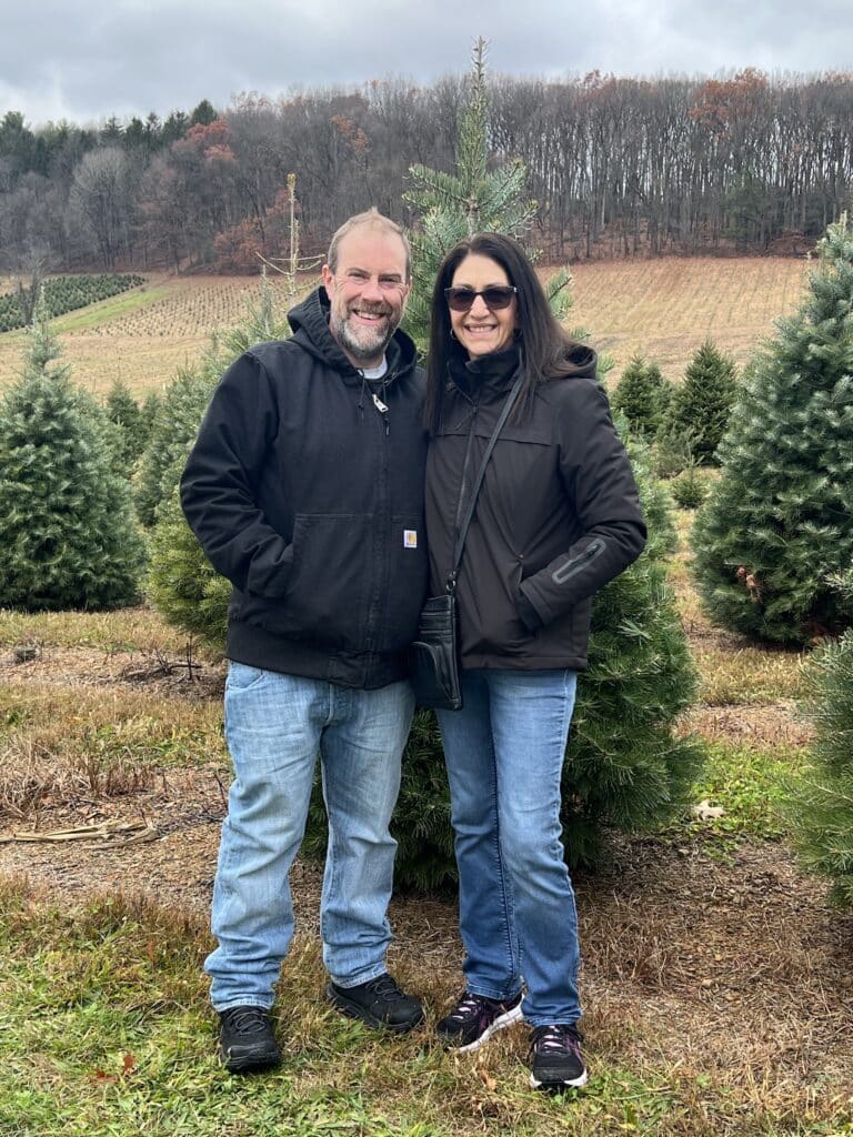 man and woman standing in front of christmas trees